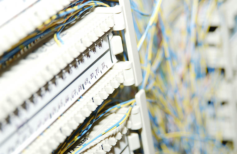 A blurred image shows network cables connected to a patch panel with handwritten labels.